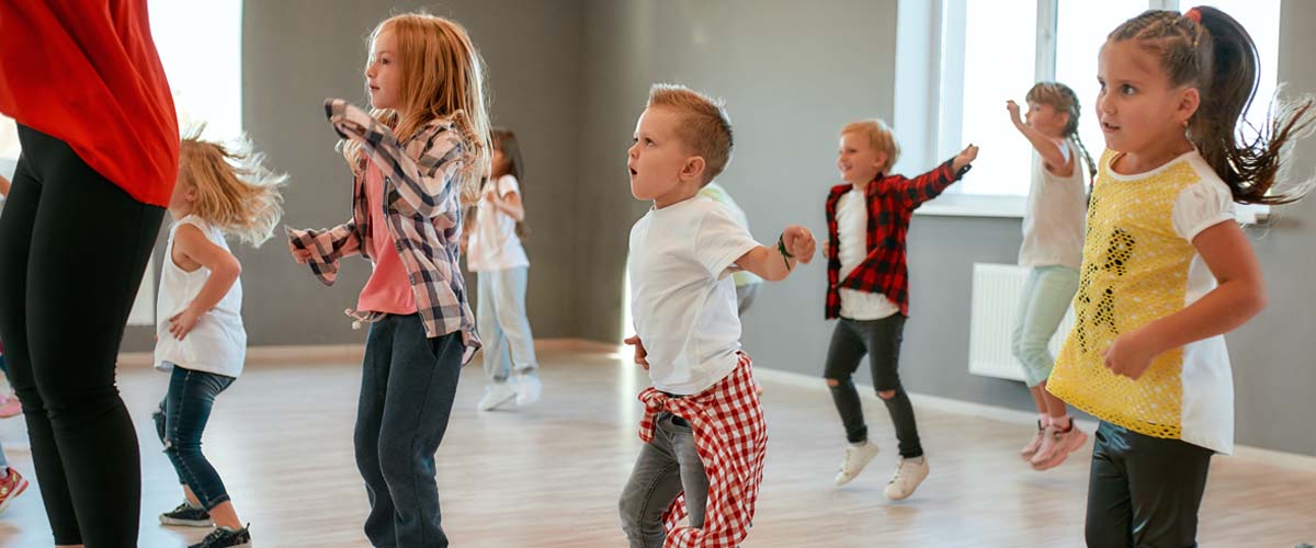 Group of little boys and girls dancing while having choreography class in the dance studio. Female dance teacher and children. Contemp dance. Hip hop. Kids and sport. Full length
